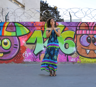 Photographie de l'artiste Daffie Doc devant un mur de graffiti.