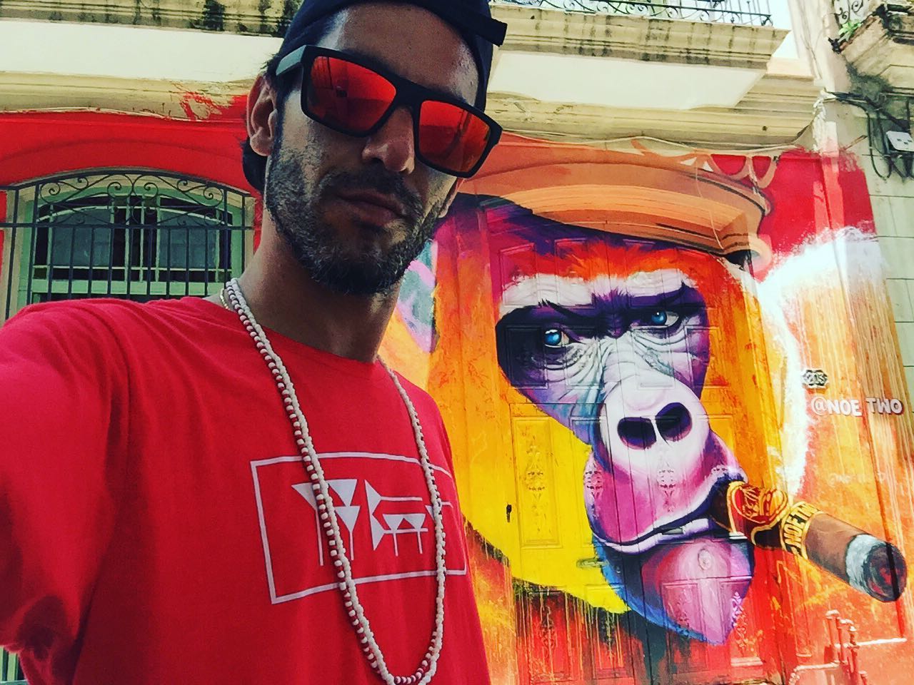 Kesh à Cuba devant un graffiti de Gorille fumant un cigare.